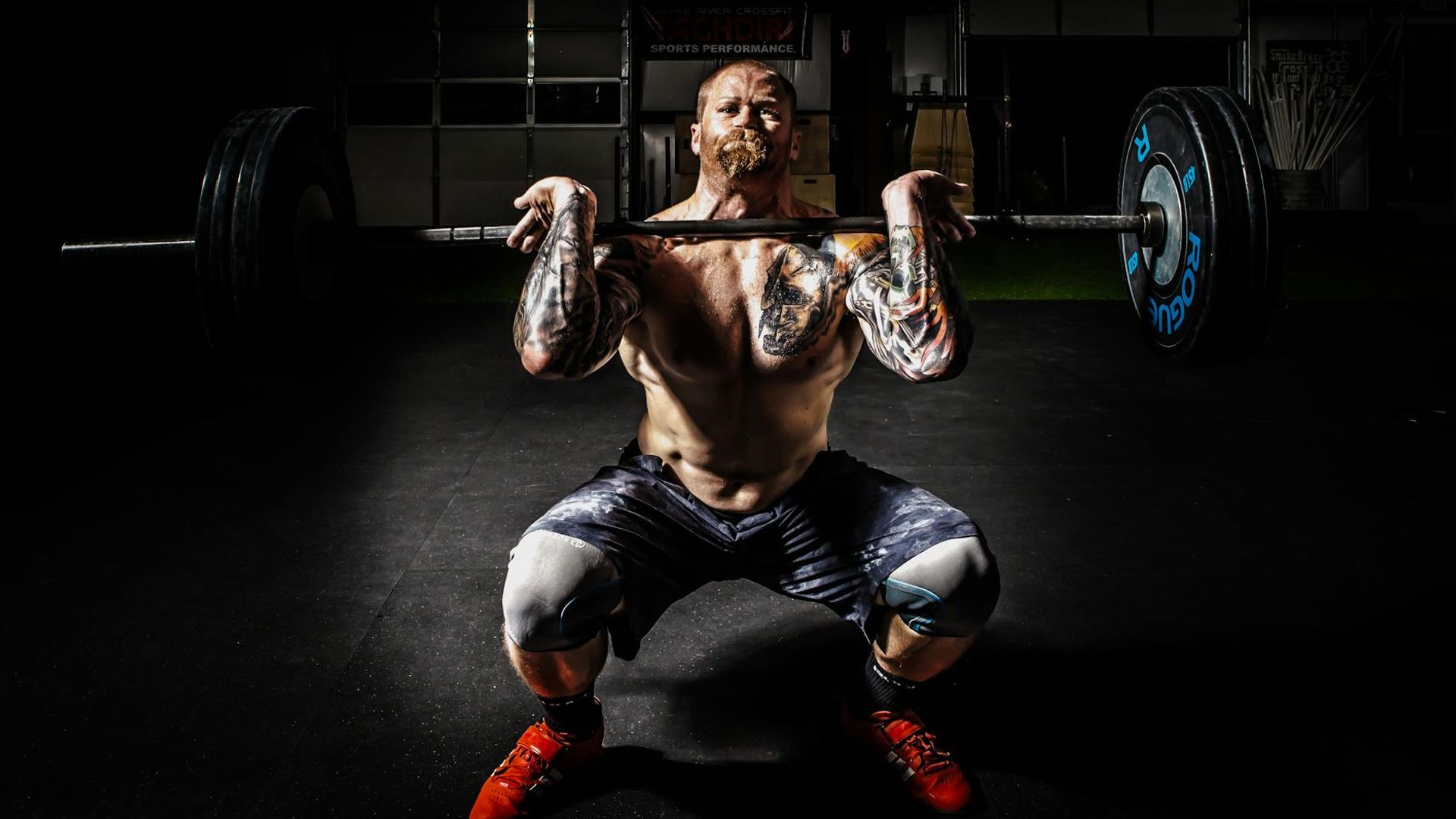 Strong man performing a weightlifting exercise in a dark gym